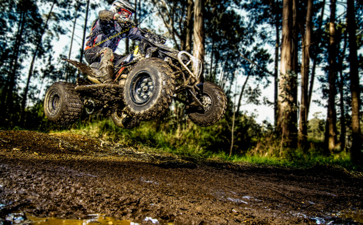 Quad,Rider,Jumping,On,A,Muddy,Forest,Trail.